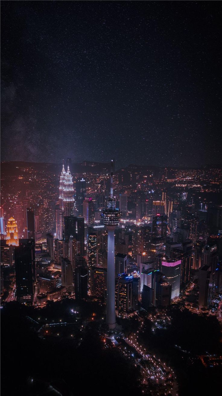 an aerial view of a city at night with lights and buildings in the foreground