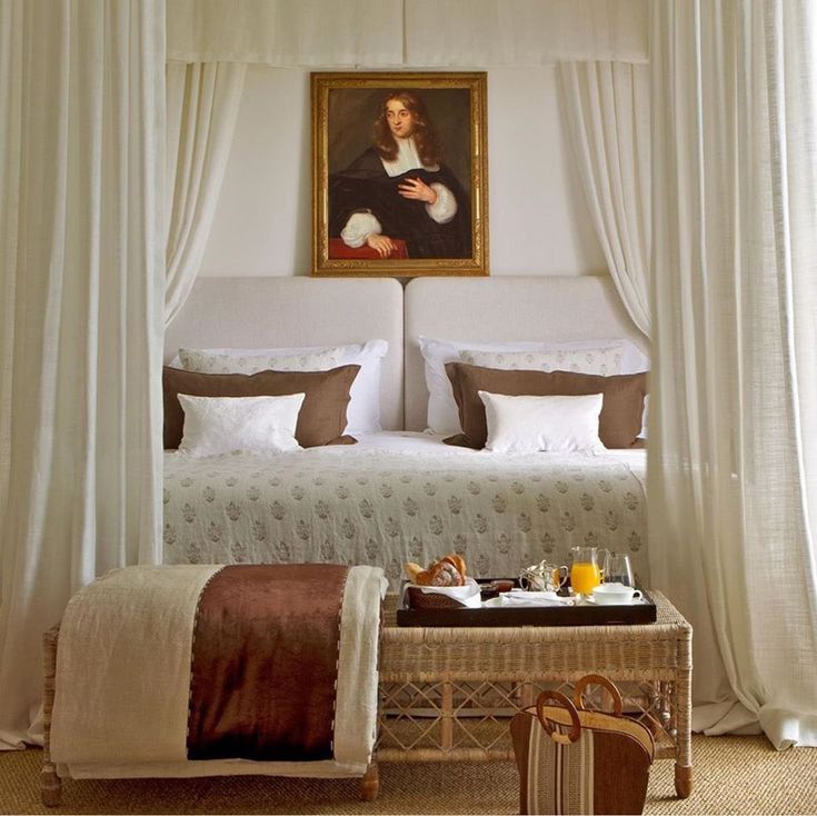 a bed with white sheets and pillows in a bedroom next to a painting on the wall