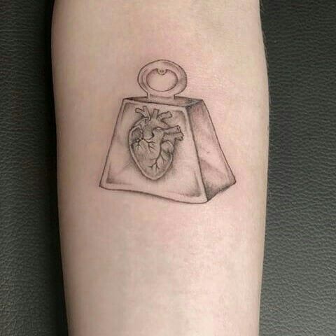 a tattoo on the leg of a woman with a heart in a purse and a ring