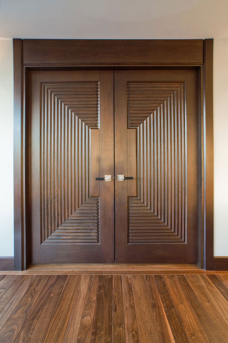 two wooden doors in the middle of a room with wood flooring and white walls