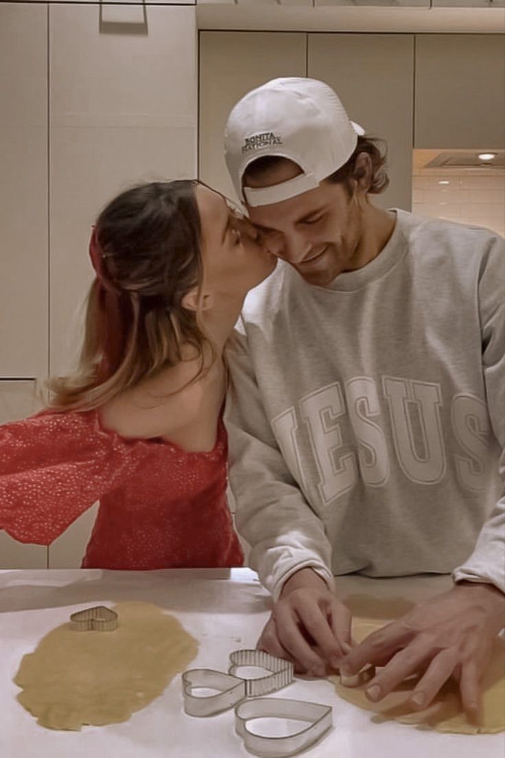 a man and woman are kissing in front of some cookie cutters