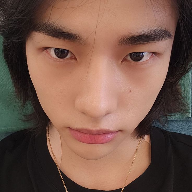 a young man wearing a black shirt and gold necklace