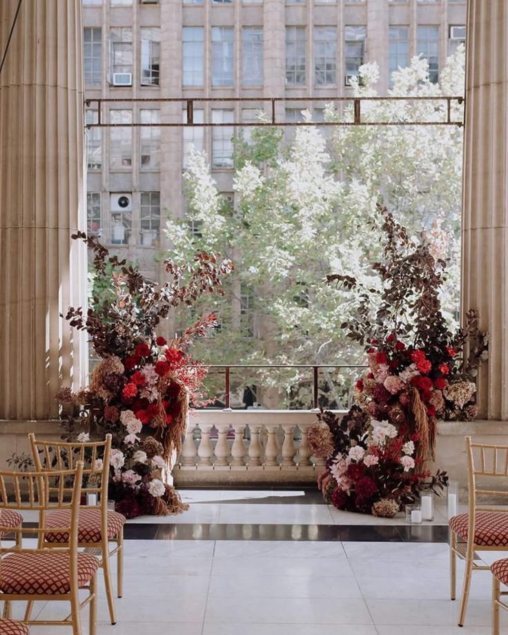 two tall vases filled with red and white flowers on top of a marble floor