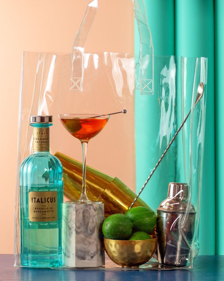 a table topped with bottles and glasses filled with alcohol next to a cocktail shaker