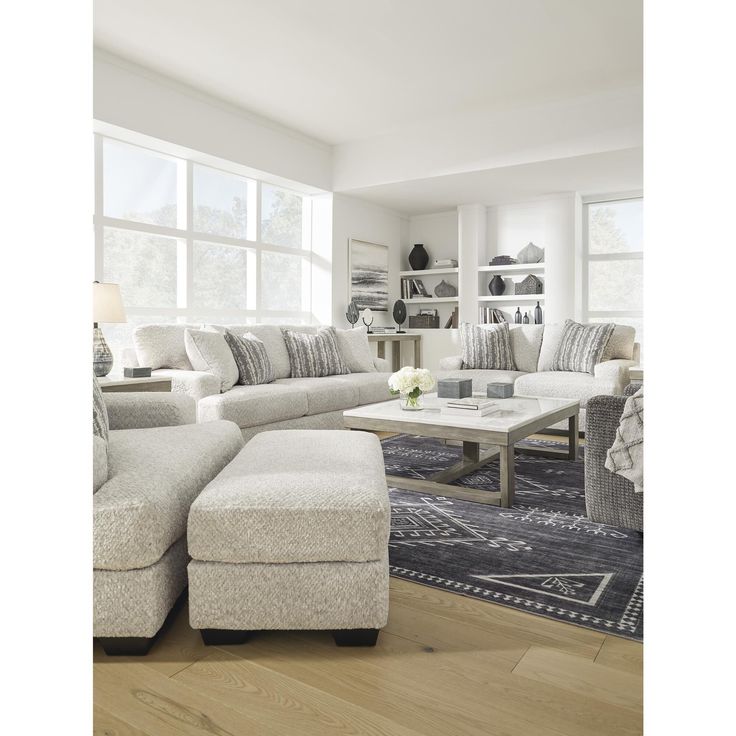 a living room filled with furniture and a rug on top of a hard wood floor