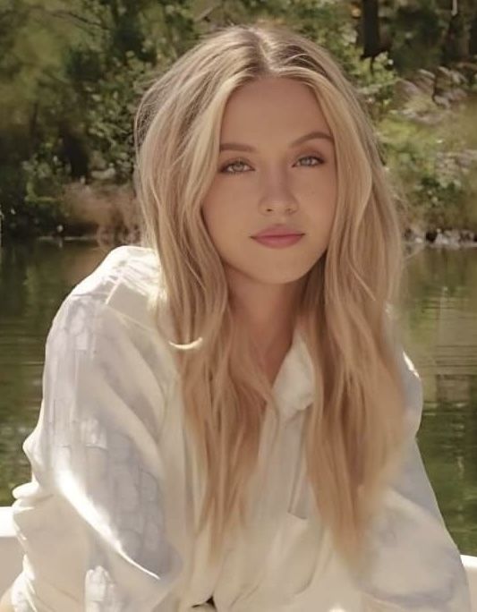 a woman sitting on top of a boat next to a body of water with trees in the background