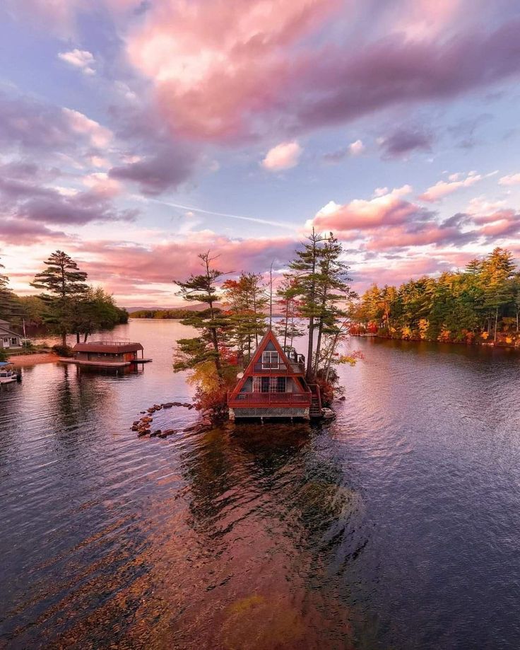 an island in the middle of a body of water with boats floating on it at sunset