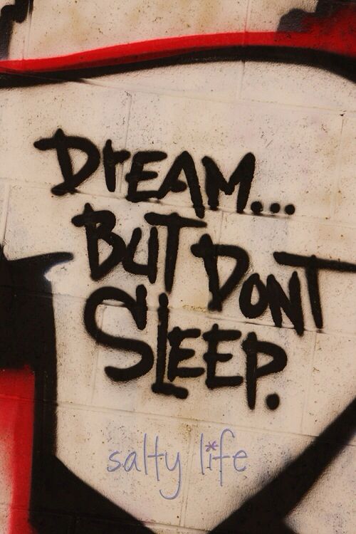 graffiti on the side of a building reads, dream but don't sleep