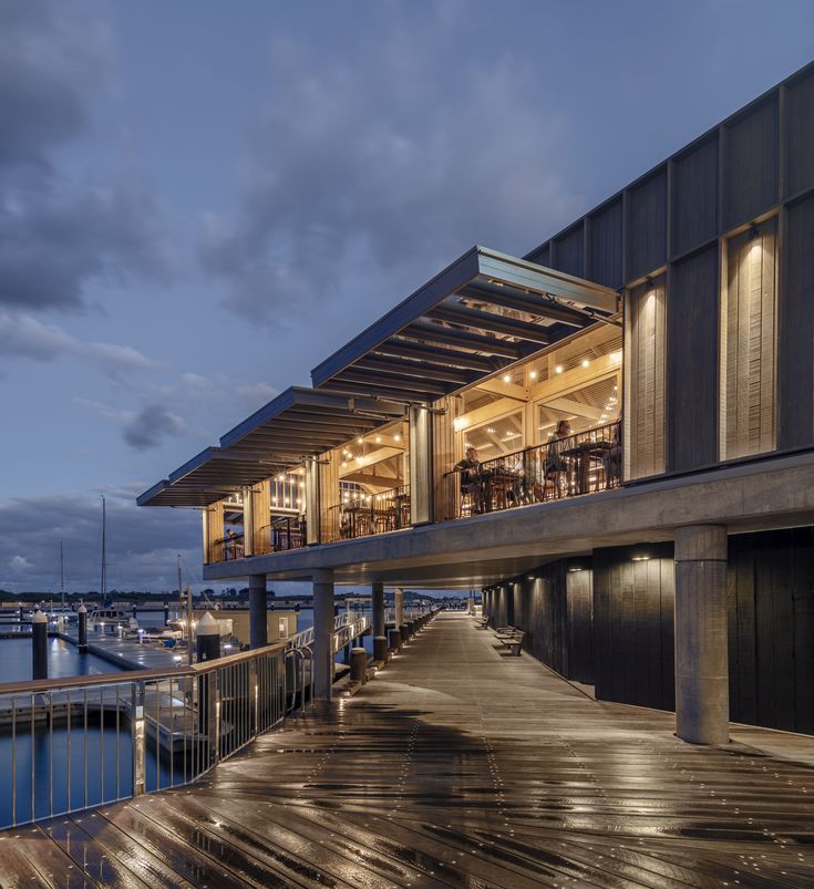 a wooden dock next to a large building with lots of lights on it's sides