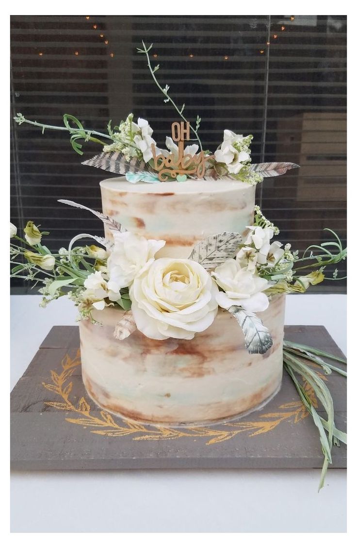 a three tiered cake with white flowers and greenery