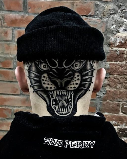 the back of a man's head with tattoos on his face and neck, wearing a black beanie