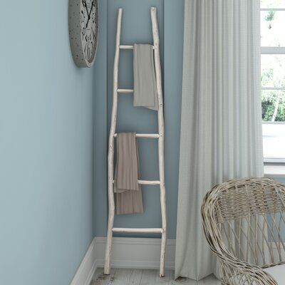 a white ladder leaning against a blue wall next to a wicker chair and clock