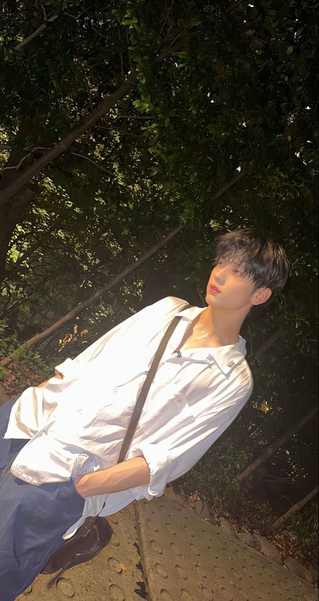 a young man wearing a white shirt and black tie holding a brown bag on his shoulder