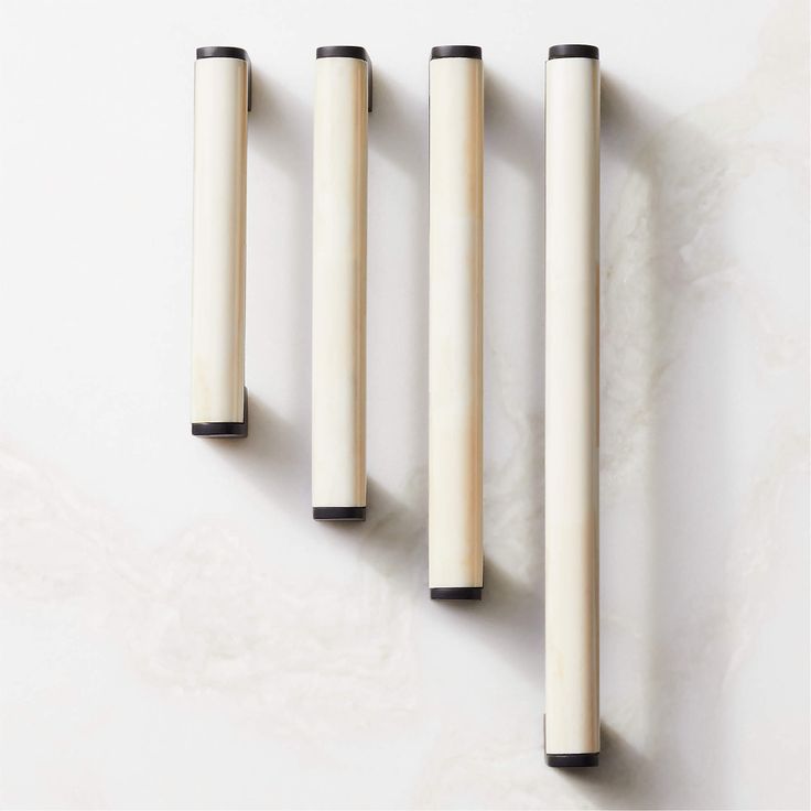 three white candles sitting on top of each other in front of a wall mounted candle holder