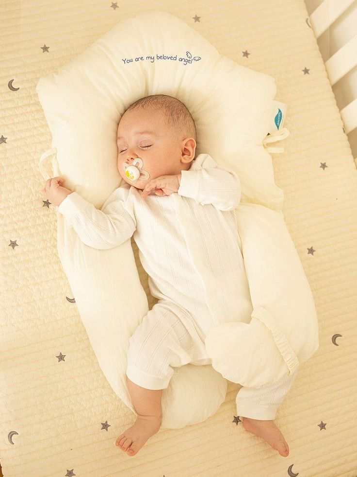 a baby sleeping on a pillow with pacifier in his mouth