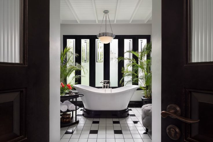 an open door leading to a bathroom with a claw foot tub and black and white checkered floor