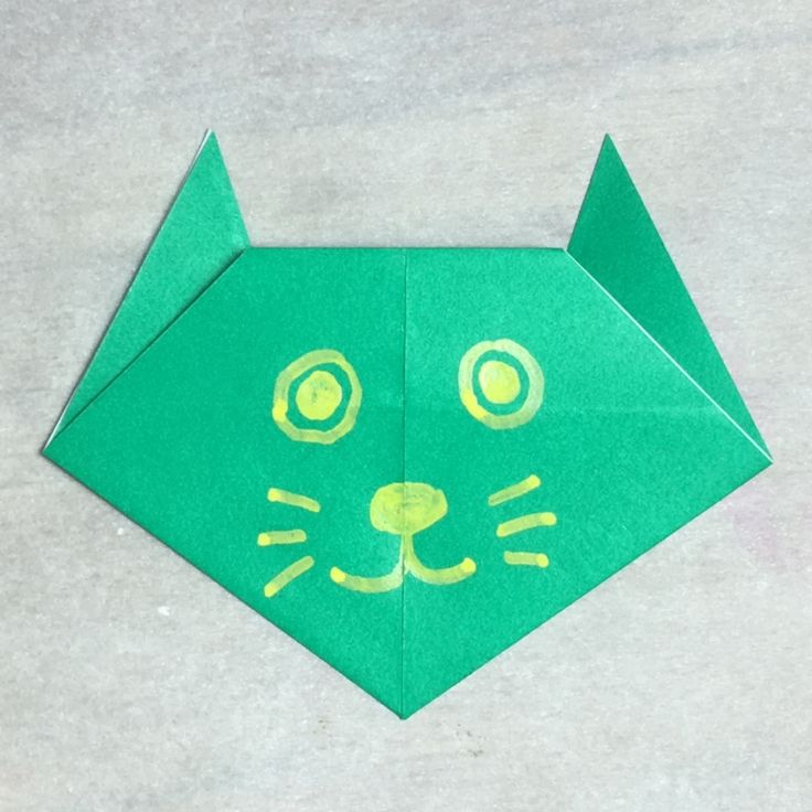 an origami cat made out of green paper with yellow eyes on it's face