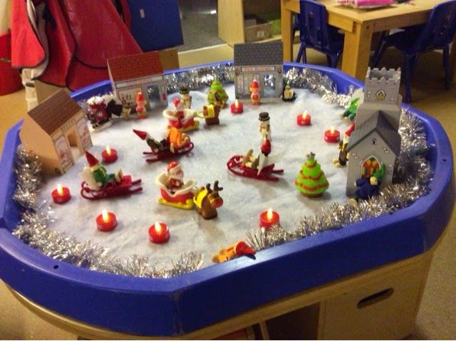 a christmas scene made out of toys and tinsel on a blue plastic table top