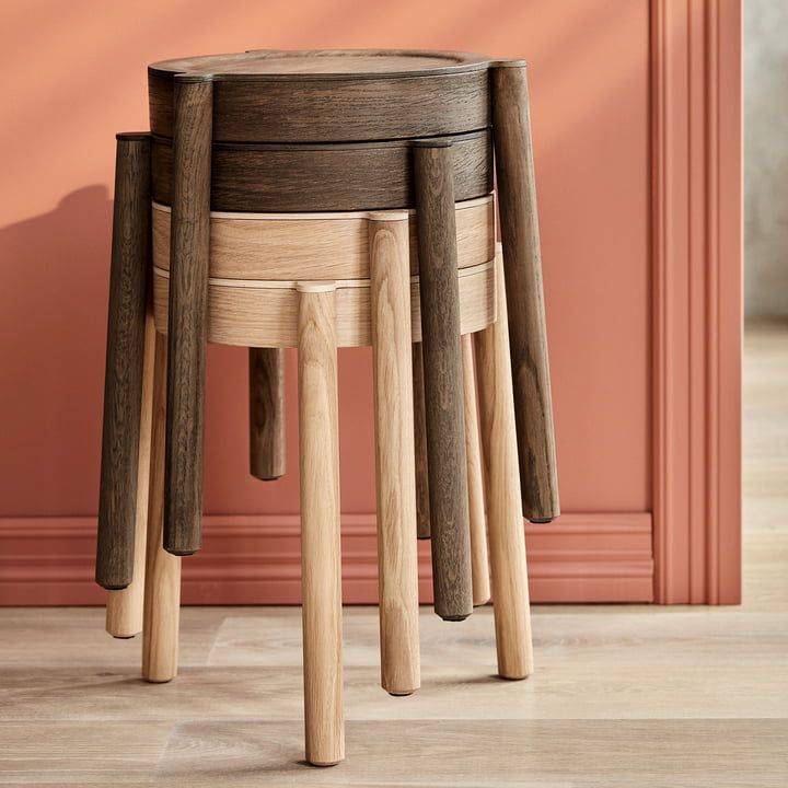 three wooden stools stacked on top of each other in front of a pink wall