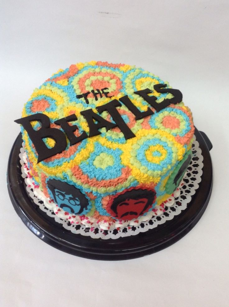 a cake with the beatles on it is sitting on a black plate and white table