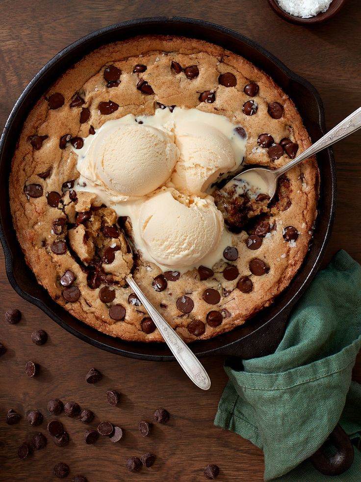 two scoops of ice cream are in a skillet with chocolate chips and cookies