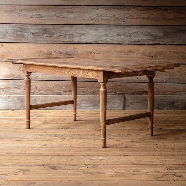 an old wooden table sitting on top of a hard wood floor next to a wall