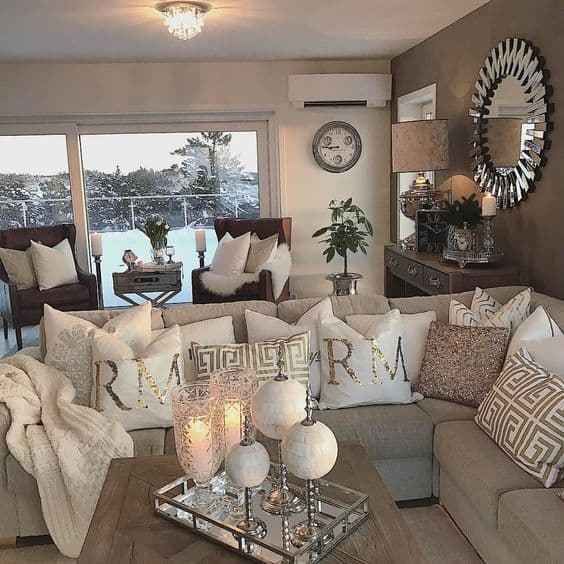 a living room filled with lots of furniture next to a large window covered in white pillows