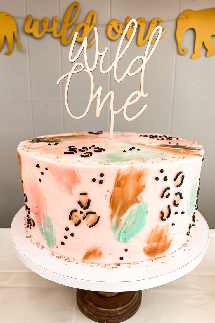 a cake that is sitting on top of a table with the words wild one written on it