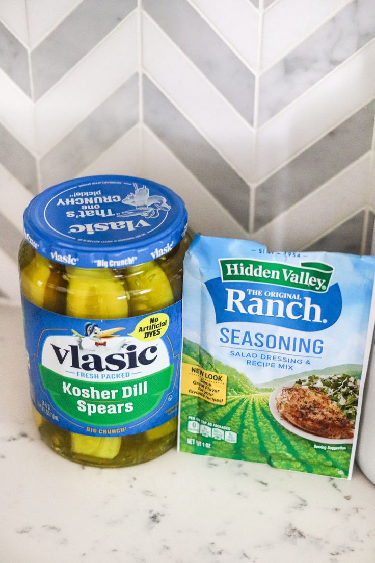 two jars of pickles and a packet of ranch seasoning sit on a counter