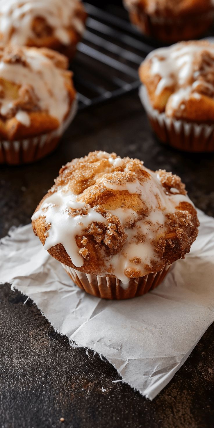 several muffins with icing sitting on top of a piece of wax paper