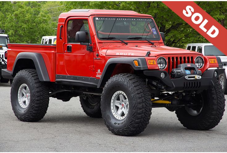 a red jeep is parked in a parking lot