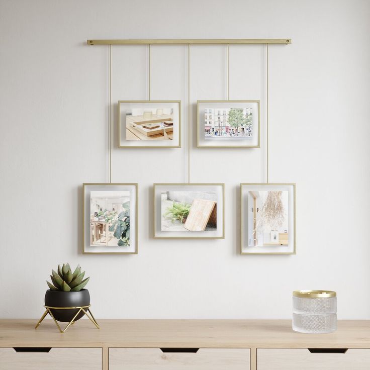 a wooden table topped with a potted plant next to pictures hanging on the wall