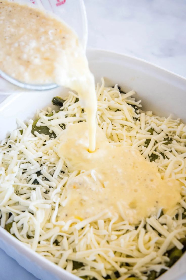 cheese being poured into a casserole dish