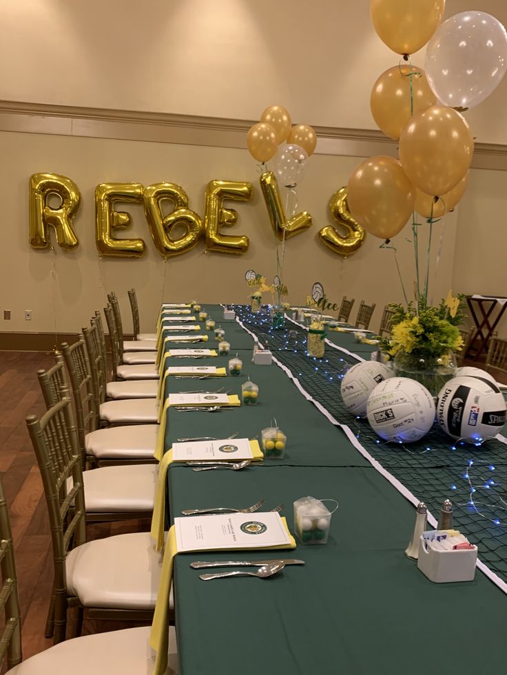 a table set up for a sports themed party with balloons and streamers on the wall