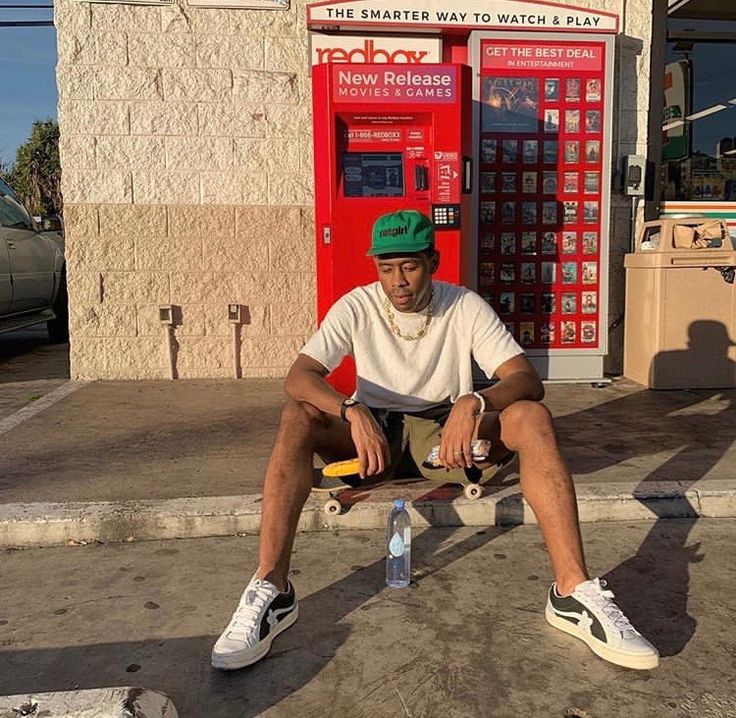 a man sitting on top of a skateboard next to a vending kiosk