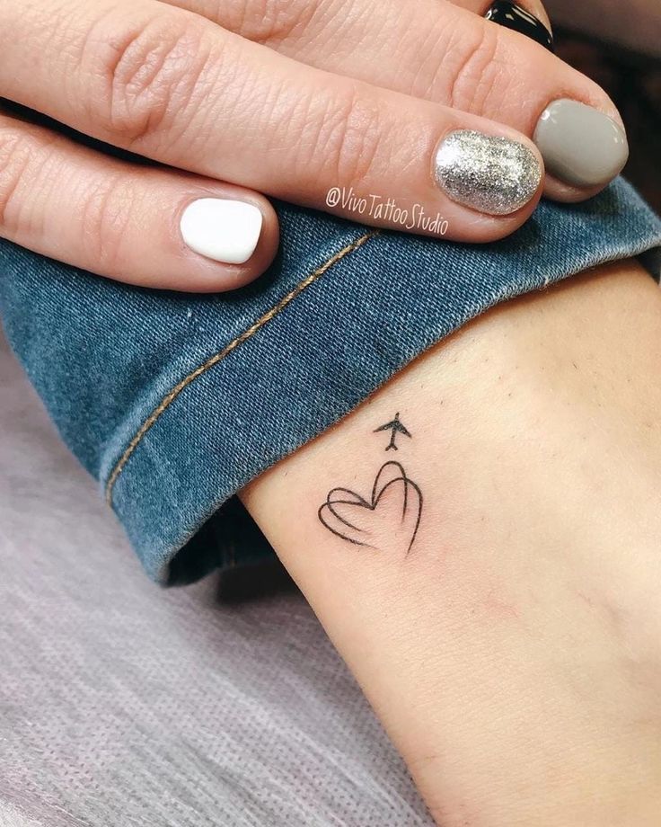 a woman's hand with a small tattoo on her left wrist and an arrow in the middle