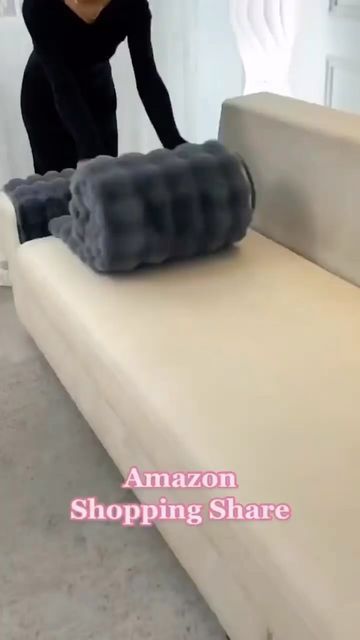 a woman in black shirt and pants cleaning a white couch with a gray pillow on it