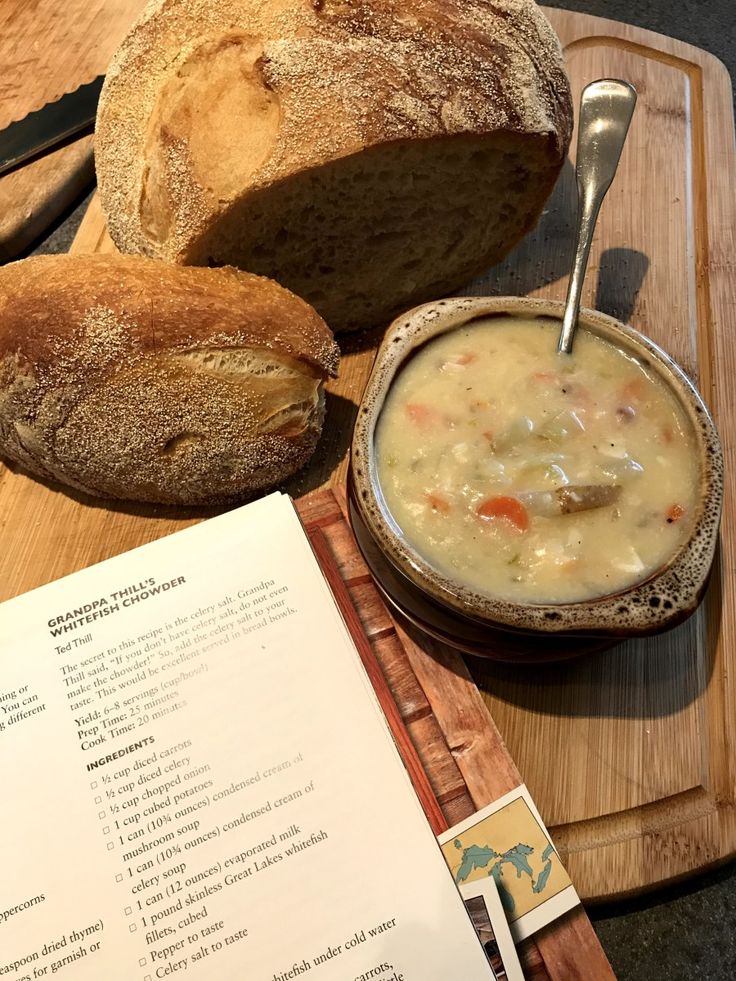 bread and soup are on a cutting board next to an open menu with a spoon