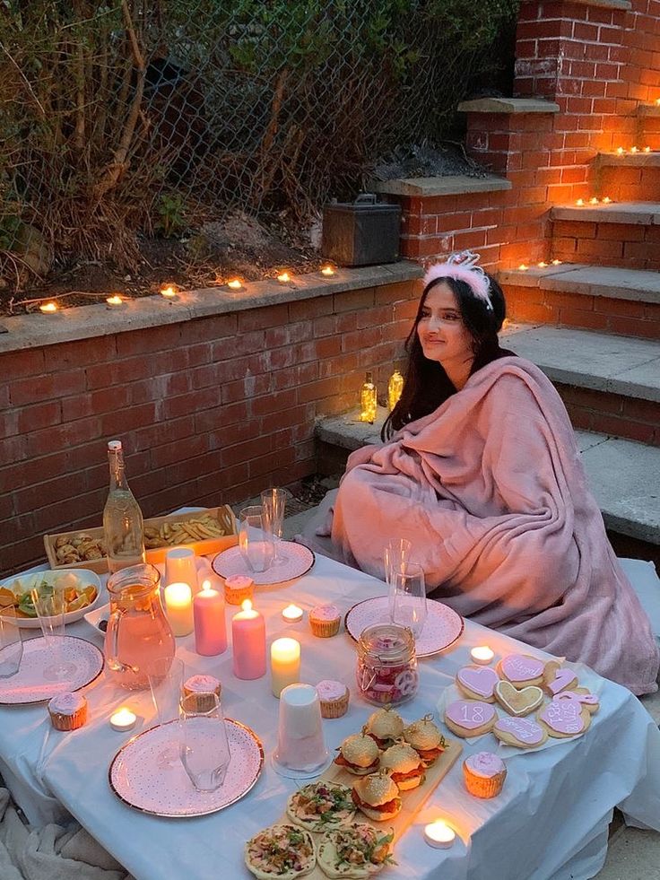 a woman sitting at a table with food and candles on it in front of her