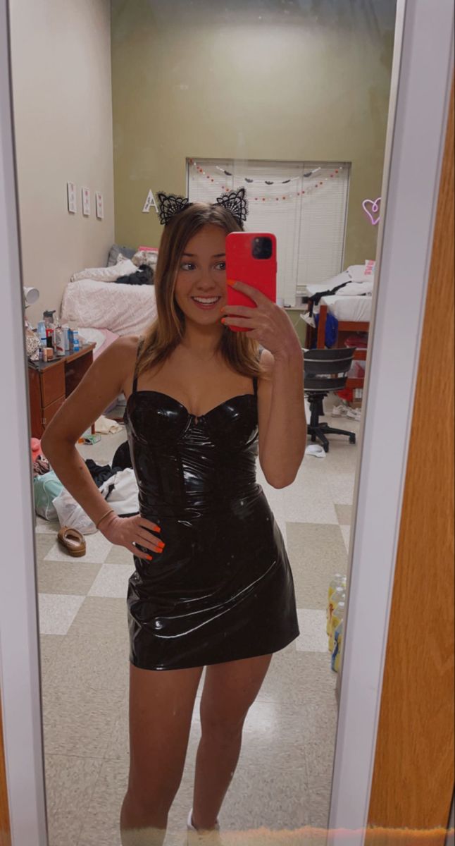 a woman is taking a selfie in the mirror wearing a latex dress and cat ears