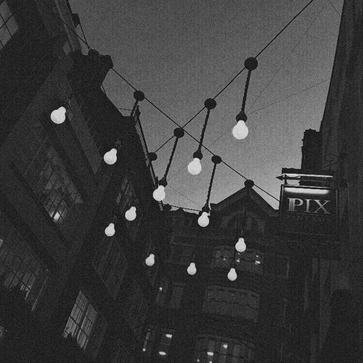 black and white photograph of lights strung from buildings