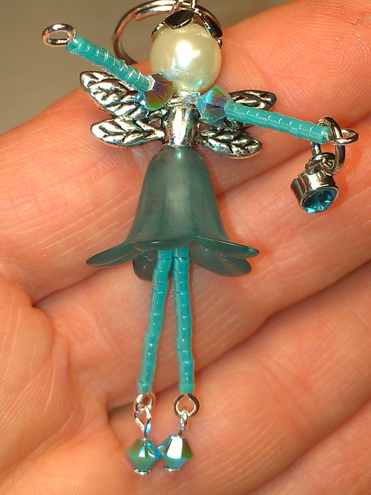 a hand holding a keychain with a little fairy on it