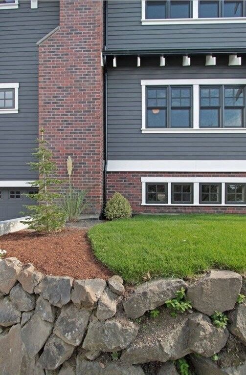 a large gray house sitting next to a lush green field