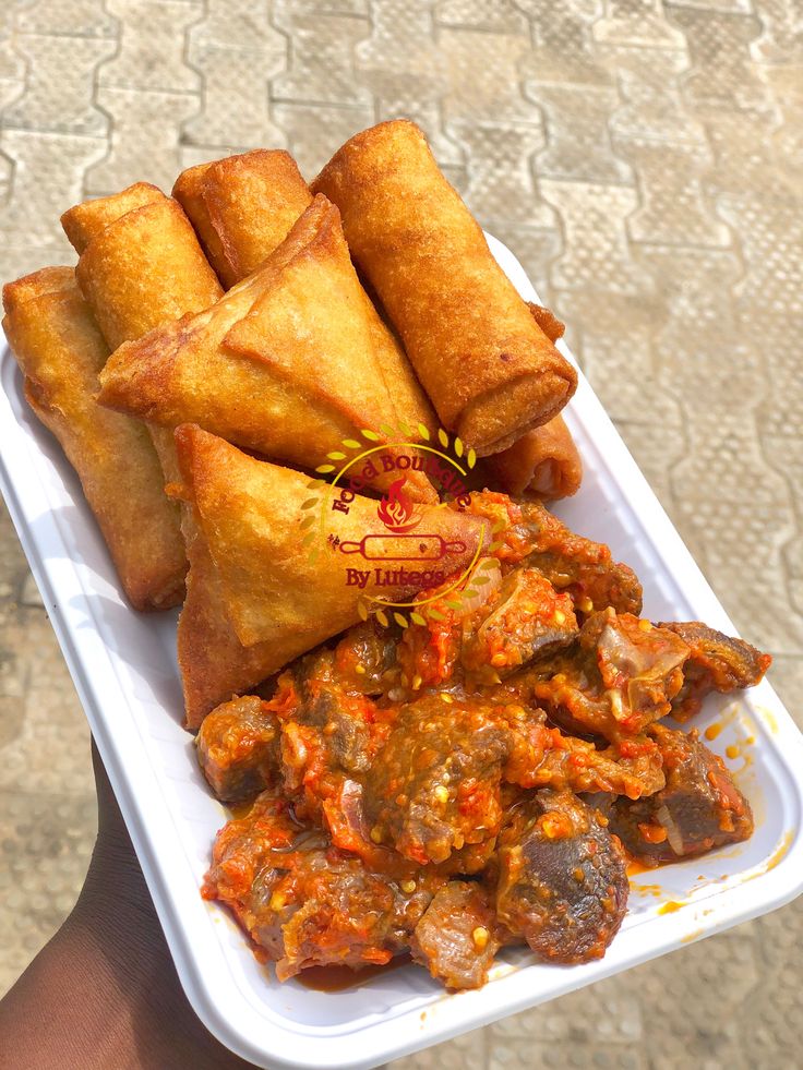 a person holding a tray with some food on it and sauce in front of them