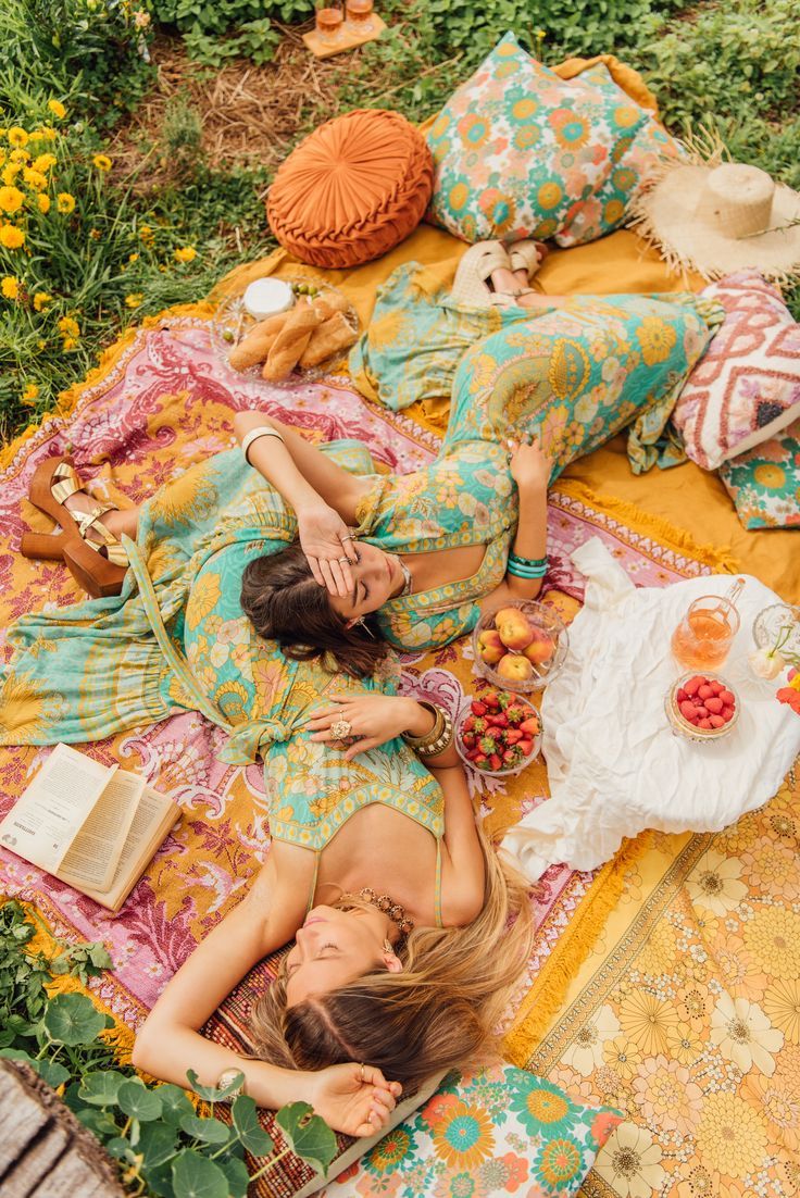 two women laying on a blanket in the grass