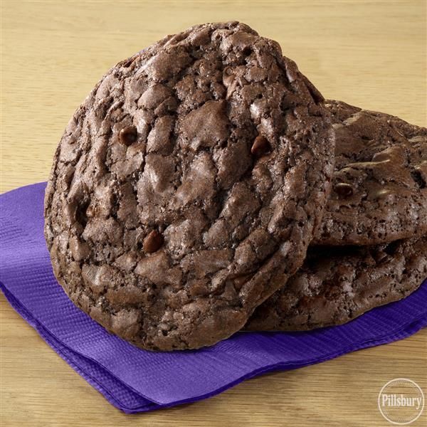 two chocolate cookies stacked on top of each other next to a purple napkin and wooden table