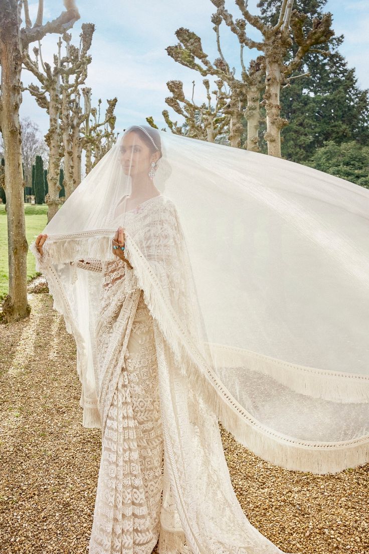 This saree features intricate embroidery in thread, pearl and sequin in a linear pattern. The saree has an exaggerated fringe. The full sleeves blouse has a plunging neckline with tassel details. This comes with an optional sheer net veil with soft fringe.From Seema Gujral's A Royal Affair collection. DELIVERY TIMEPlease allow 8-12 weeks for your outfit to arrive. FABRIC DETAILSNet Professional cleaning only. Elegant Festive Saree With Tassels, Festive Saree Blouse Piece With Tassels, Bollywood Style Saree With Tassels For Reception, Designer Bollywood Saree With Tassels, Elegant Saree With Tassels For Reception, Bollywood Blouse Piece With Tassels In Traditional Drape, Pre-draped Saree With Tassels For Wedding, Bollywood Blouse Piece With Traditional Drape And Tassels, Elegant Wedding Saree With Tassels