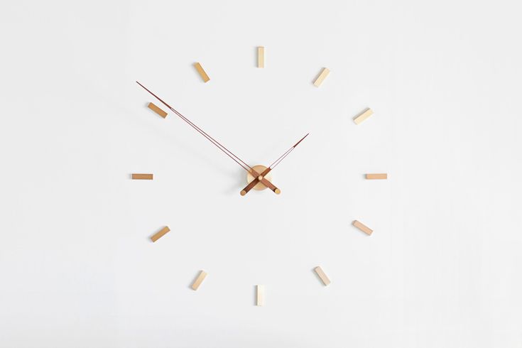 a clock made out of wood sticks on a white surface with the numbers six to twelve