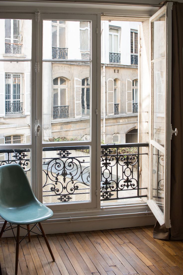 a blue chair sitting on top of a hard wood floor next to a large window