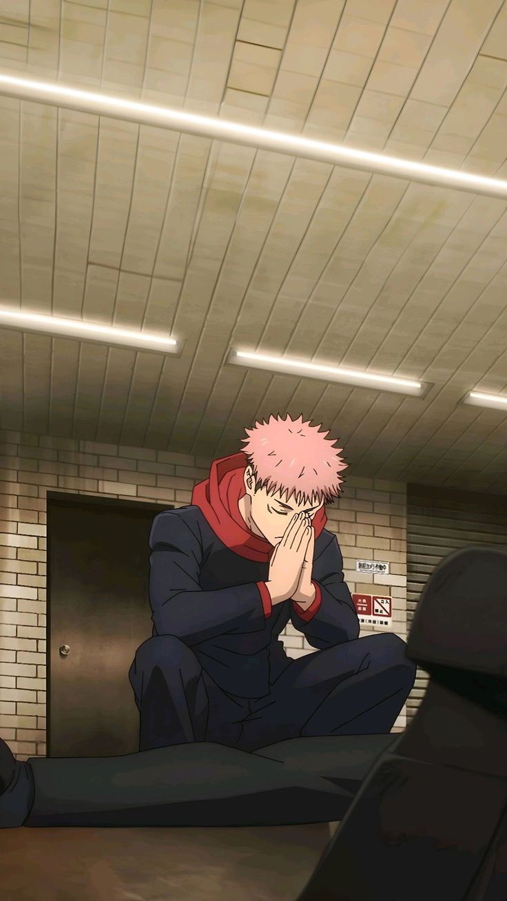 a man with pink hair sitting on top of a floor next to a brick wall